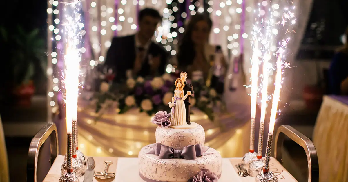 Wedding couple cutting cake with ambient lighting and elegant reception setup