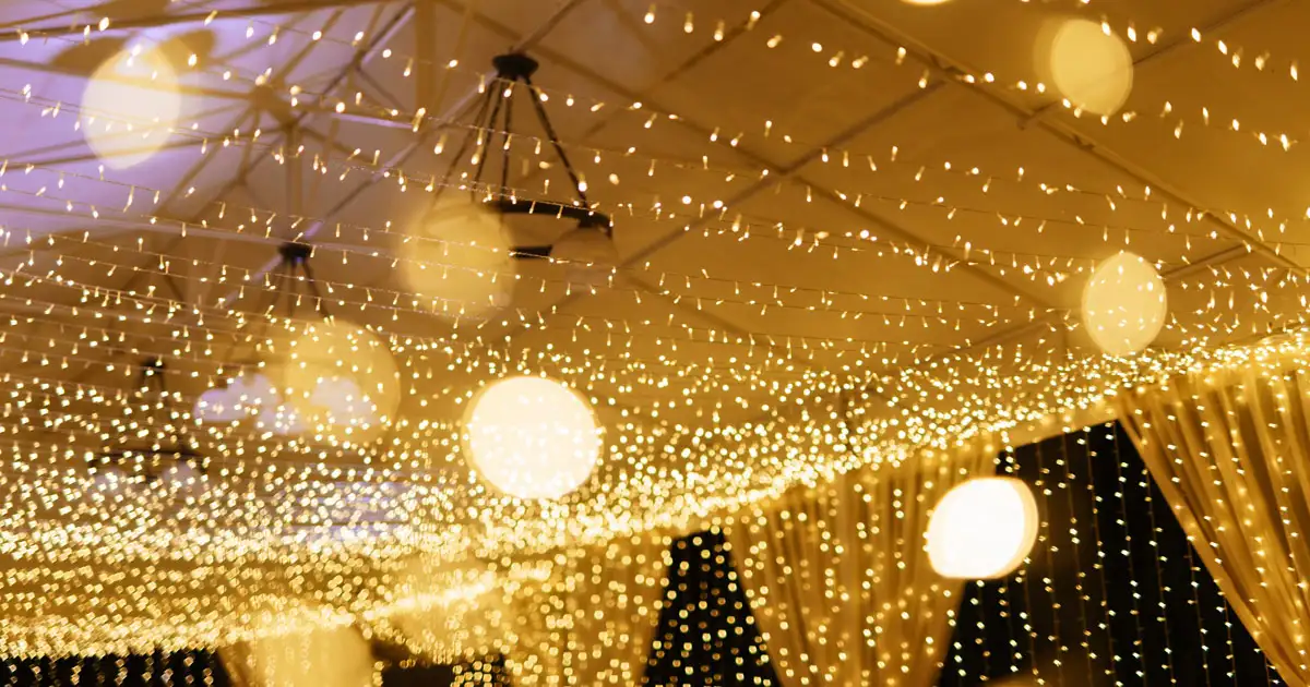 Wedding ceremony setup with string lights and floral arch creating romantic lighting scene