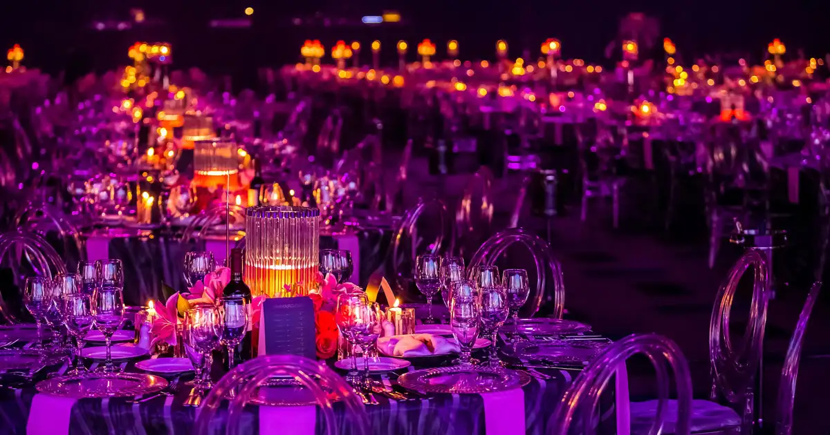 Bride and groom seated at reception table with warm string lighting backdrop